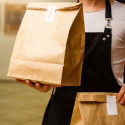 Two boxes with fast food being carried by delivery man in unifor