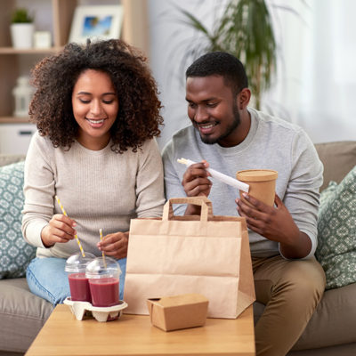 happy couple with takeaway food and drinks at home