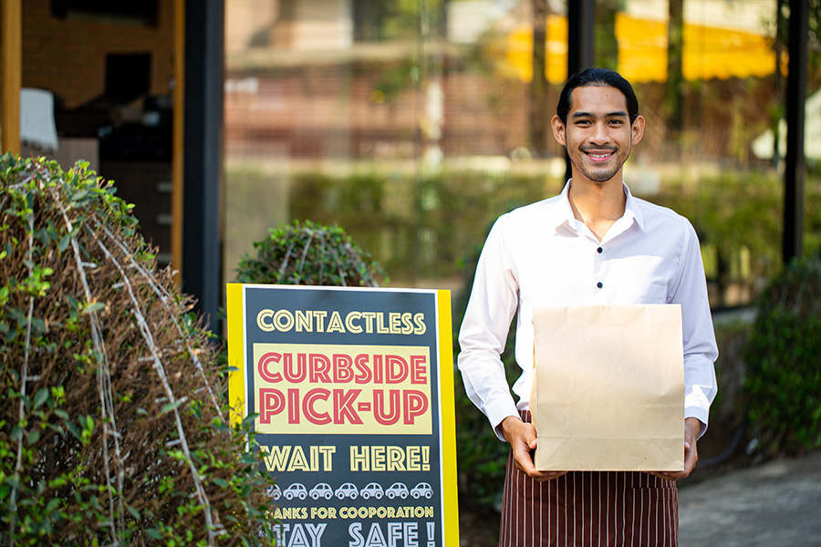 Curbside pick up.Store worker smiling to prepare and hold foods from customer order online delivery to customer in the outside.Social distance and contactless prevent covid-19.