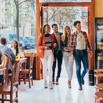 Full shot of a interracial group enters a restaurant